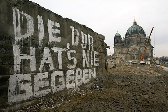 Die Aufnahme von Arno Burgi stammt aus dem Jahr 2008. Es zeigt eine Mauer der Br&uuml;cke Rathausstra&szlig;e auf der in wei&szlig;er Farbe geschrieben steht Die DDR hat&acute;s nie gegeben. Im Hintergrund ist der Berliner Dom zu sehen, dazwischen die Brache, auf der einst der Palast der Republik gestanden hat. Das Foto darf bis zum 31. Dezember 2025 im Rahmen der Berichterstattung &uuml;ber die Ausstellung Aufarbeitung.  (Foto: picture alliance / dpa / Arno Burgi)