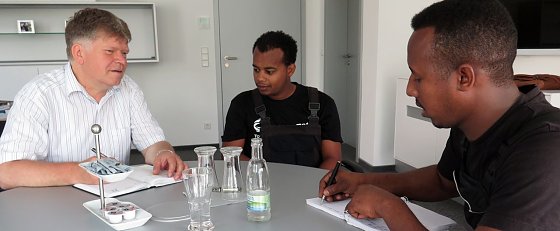 Bild: Biniam Teklay (rechts) und Michael Teclom Aslamesh im Gespr&auml;ch mit dem Ausbildungsverantwortlichen Achit T&ouml;lle.