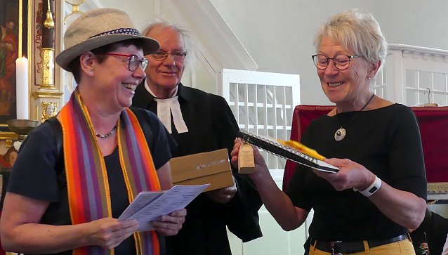 Bild: nes Delert, Gemeindep&auml;dagogin und Initiatorin des regionalen Pilgerns, &uuml;berreicht eine Fl&auml;schchen-Replik an Pilgerin Brigitte Hoppe aus Werningerode, die alle 23 Kirchen der Region besucht hat. Im Gegenzug erh&auml;lt die Gemeinde von ihr ein Fotoalbum ihrer Tour. In der Mitte Pfarrer i.R. Ehrhart Neubert.