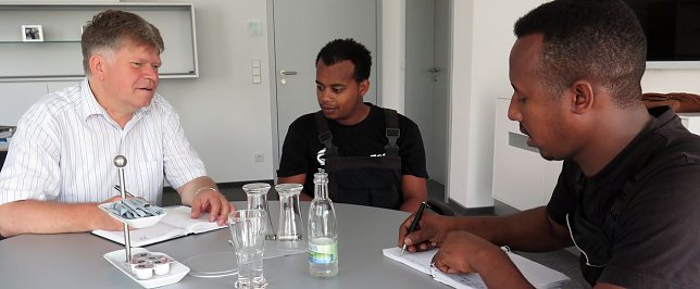 Bild: Biniam Teklay (rechts) und Michael Teclom Aslamesh im Gespr&auml;ch mit dem Ausbildungsverantwortlichen Achit T&ouml;lle.