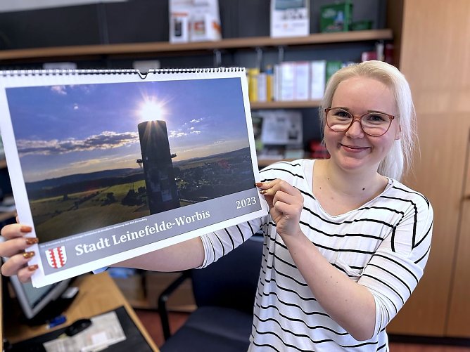 Stadtmitarbeiterin Michelle Enge mit dem neuen Jahreskalender 2023, der ab sofort in den B&uuml;rgerb&uuml;ros erh&auml;ltlich ist.  (Foto: Ren&eacute; Wei&szlig;bach)